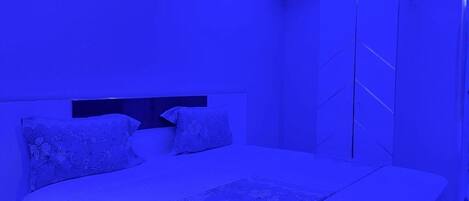A bedroom with a bed, a nightstand, a wardrobe, and an air conditioning unit.