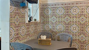 Zona pranzo con tavolo, sedie e televisore a parete.