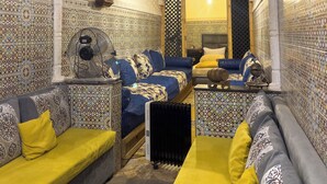 Una stanza con pareti decorate, un divano, un letto e una ventola a soffitto.