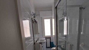Une salle de bain moderne avec une douche à parois de verre, un lavabo blanc et des toilettes.
