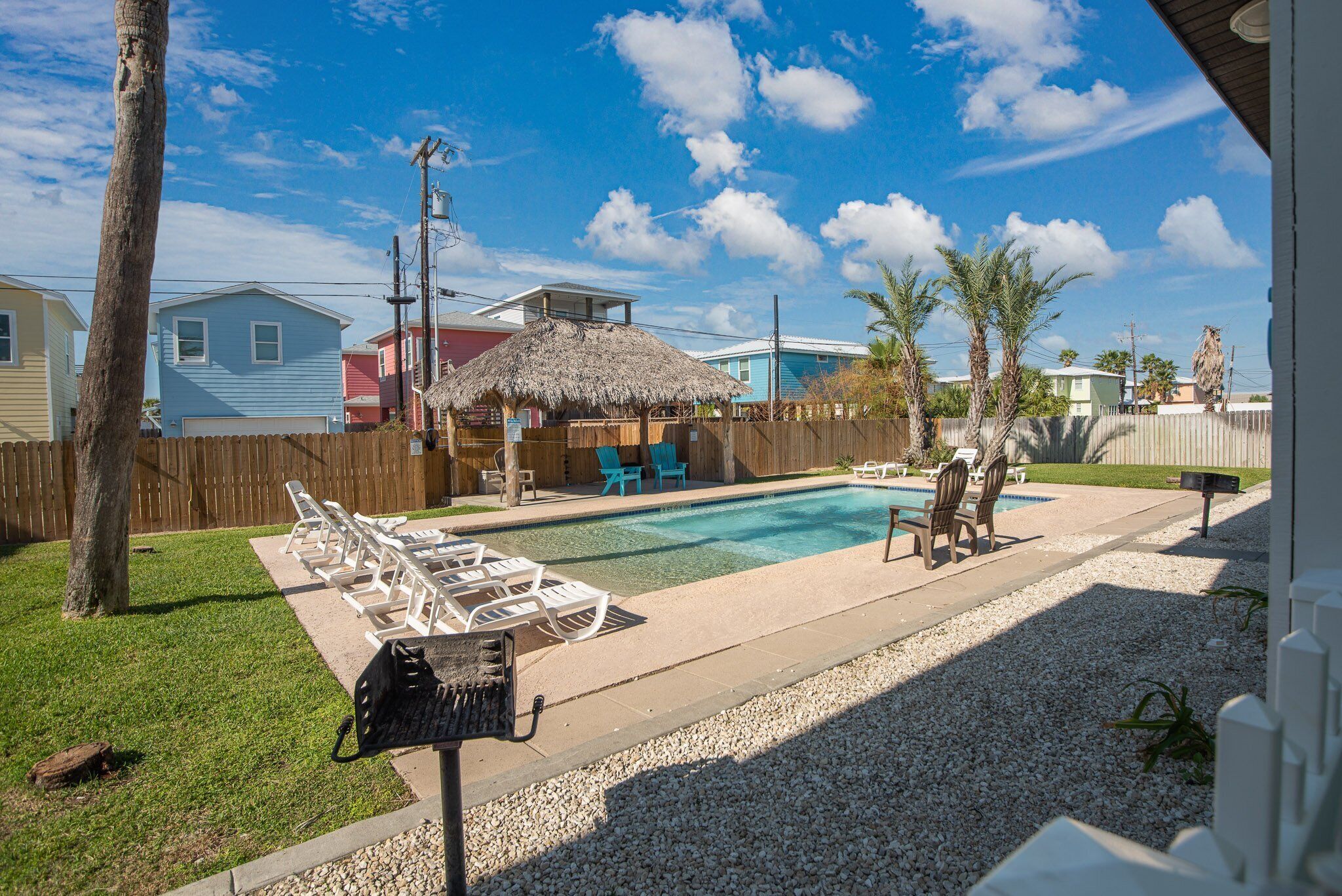 Un jardin avec une piscine, des chaises longues et un barbecue.