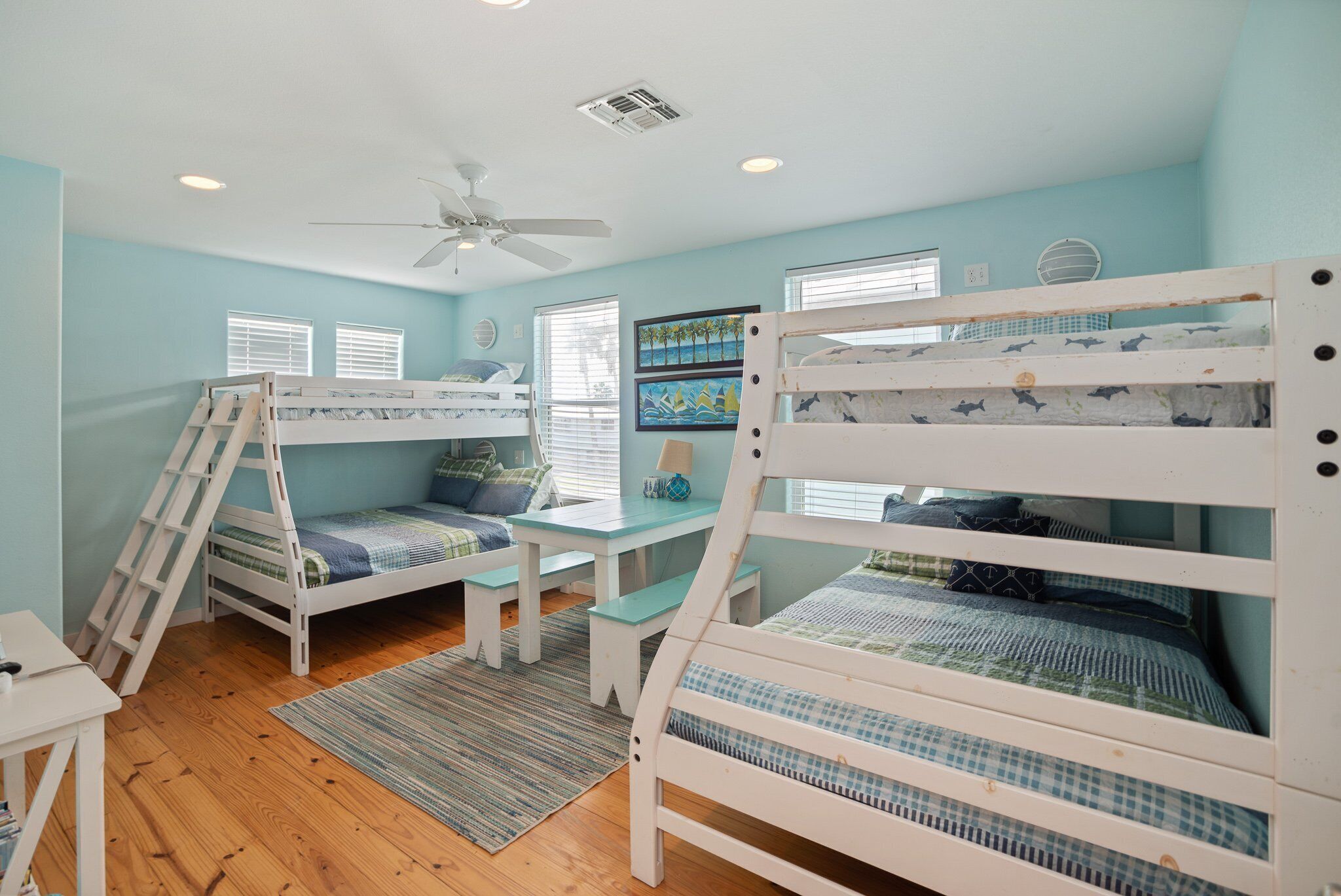A child’s bedroom with bunk beds, a desk, and a ceiling fan.