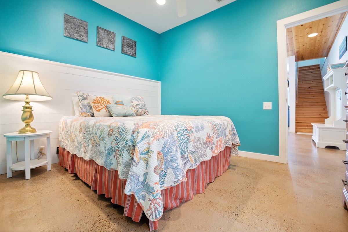 Quarto com cama, mesa de cabeceira, abajur e escada que d á para outro andar.