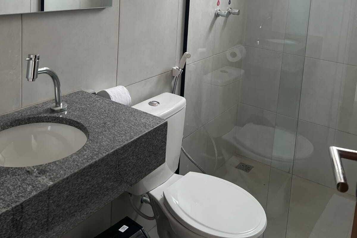 A modern bathroom with a granite countertop sink, a white toilet, and a glass shower enclosure.
