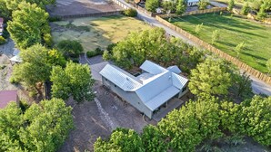 Una vista aerea di una proprietà con un edificio grande, circondata da alberi e un campo recintato.