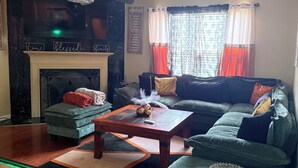 Una sala de estar con chimenea, un sofá, una mesa de centro y una televisión.