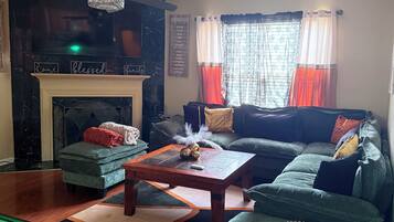 Una sala de estar con chimenea, un sofá, una mesa de centro y una televisión.