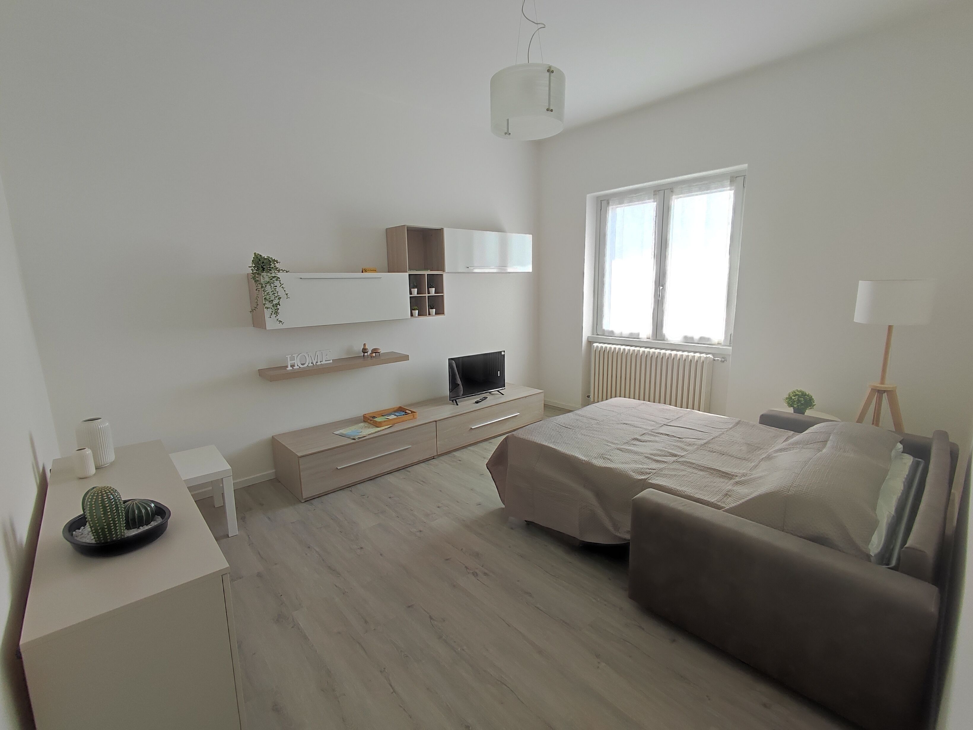 Une chambre à coucher moderne avec un lit, une télévision, un bureau et une fenêtre.