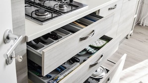 Una cocina moderna con armarios blancos, una estufa a gas y un horno empotrado.