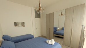 Un dormitorio con dos camas, un armario y una araña.