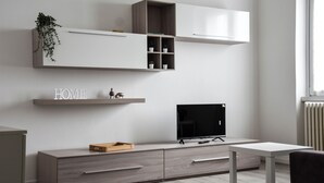 Una sala de estar moderna con un televisor de pantalla plana, un mueble de madera y un estante blanco con la palabra “HOME”.