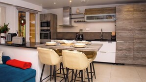 Uma cozinha moderna com uma ilha central, banquetas de bar e um espaço para refeições.