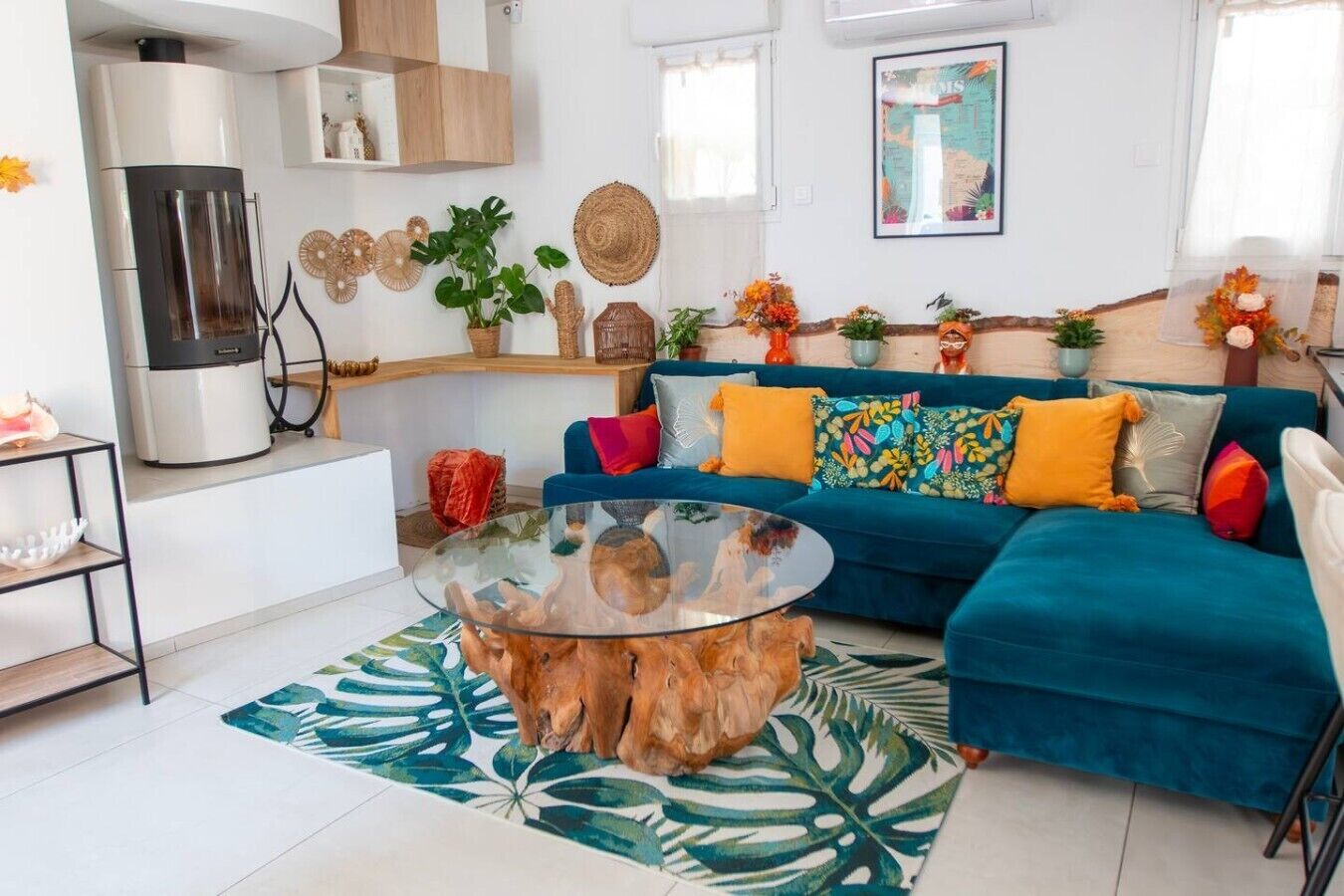 Una sala de estar moderna con un sofá azul, una mesa de centro de vidrio y una zona de cocina con refrigerador y estufa.