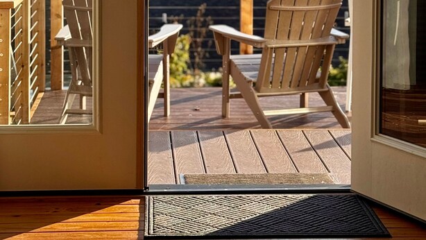 A wooden deck with a chair and a table, overlooking a forested valley. - Ocean Cove Inn #8 - Ocean View (Yachats)