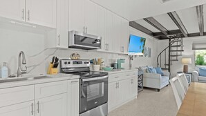 Een moderne keuken met witte kastjes, roestvrijstalen apparatuur en een ingebouwde televisie.