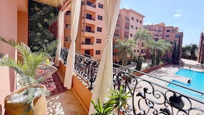 A balcony with a view of a swimming pool and adjacent buildings. - Menara Palms Marrakech (Marrakech)