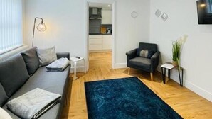 A modern living room with a grey sofa, a blue rug, and a small side table. - Prosper House Apartment 1 - Stylish City living (Norwich)