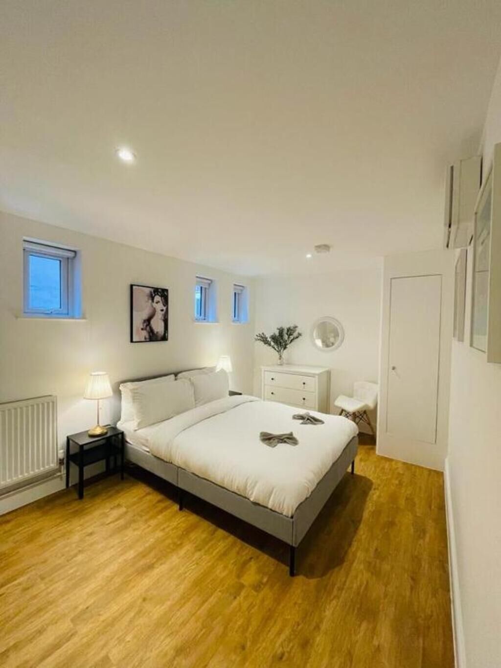 Ein Schlafzimmer mit einem Bett, Nachttischen, einem Heizkörper, einem Fenster und einer Tür.
