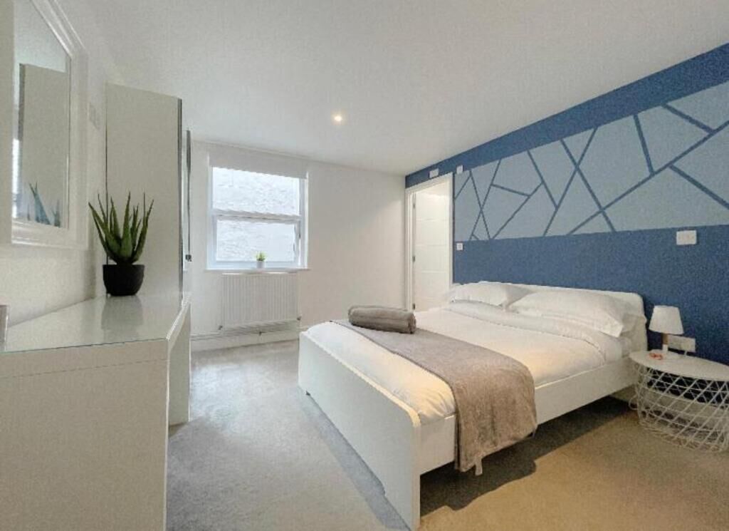A modern bedroom with a bed, bedside table, and a window.