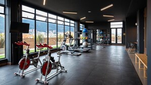Ein Fitnessstudio mit Laufbändern, Gewichten und großen Fenstern mit Blick auf die Stadt.