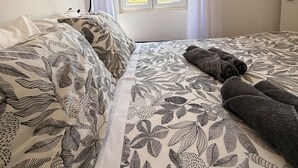 A bedroom with a bed, a window with curtains, and a wall-mounted phone. - Naval Marina View Apartment 1 (Vila do Conde)