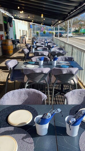 An outdoor café with tables and chairs, some with tablecloths, and a few with placemats. - Naval Marina View Apartment 1 (Vila do Conde)