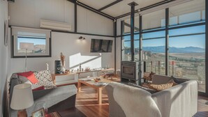 A modern living room with a large window, a fireplace, and a flat-screen TV. - Casa Altos del Ñirihuau - Panoramic Refuge (Dina Huapi)