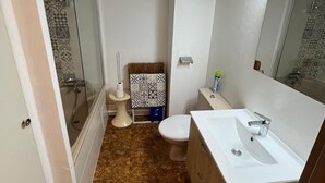 Un baño pequeño con ducha, inodoro y lavamanos.