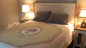 Ein ordentlich bezogenes Bett mit einer Bettdecke, zwei Nachttischlampen und einem kleinen Schrank.
