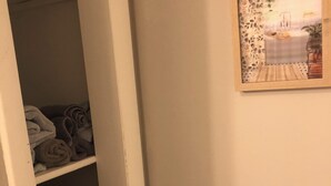 Ein Zimmer mit einem Schrank, der gefaltete Handtücher und ein Bild einer Strandlandschaft an der Wand zeigt.