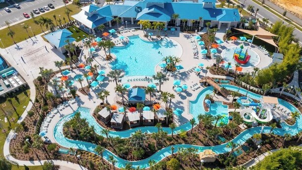 En vy från ovan av ett semesterområde med en stor pool i mitten, flera mindre pooler och en vattenrutschkana.