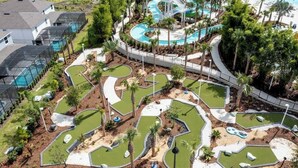 En golfbana med flera puttinggreener, en swimmingpool och omgivande palmer.