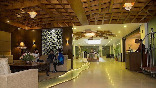 A spacious lobby with a high ceiling, a reception desk, and a seating area with a decorative wall. - Hotel Buddy (Kathmandu)