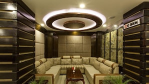A modern living room with a sectional sofa, a wooden coffee table, and two potted plants. - Hotel Buddy (Kathmandu)