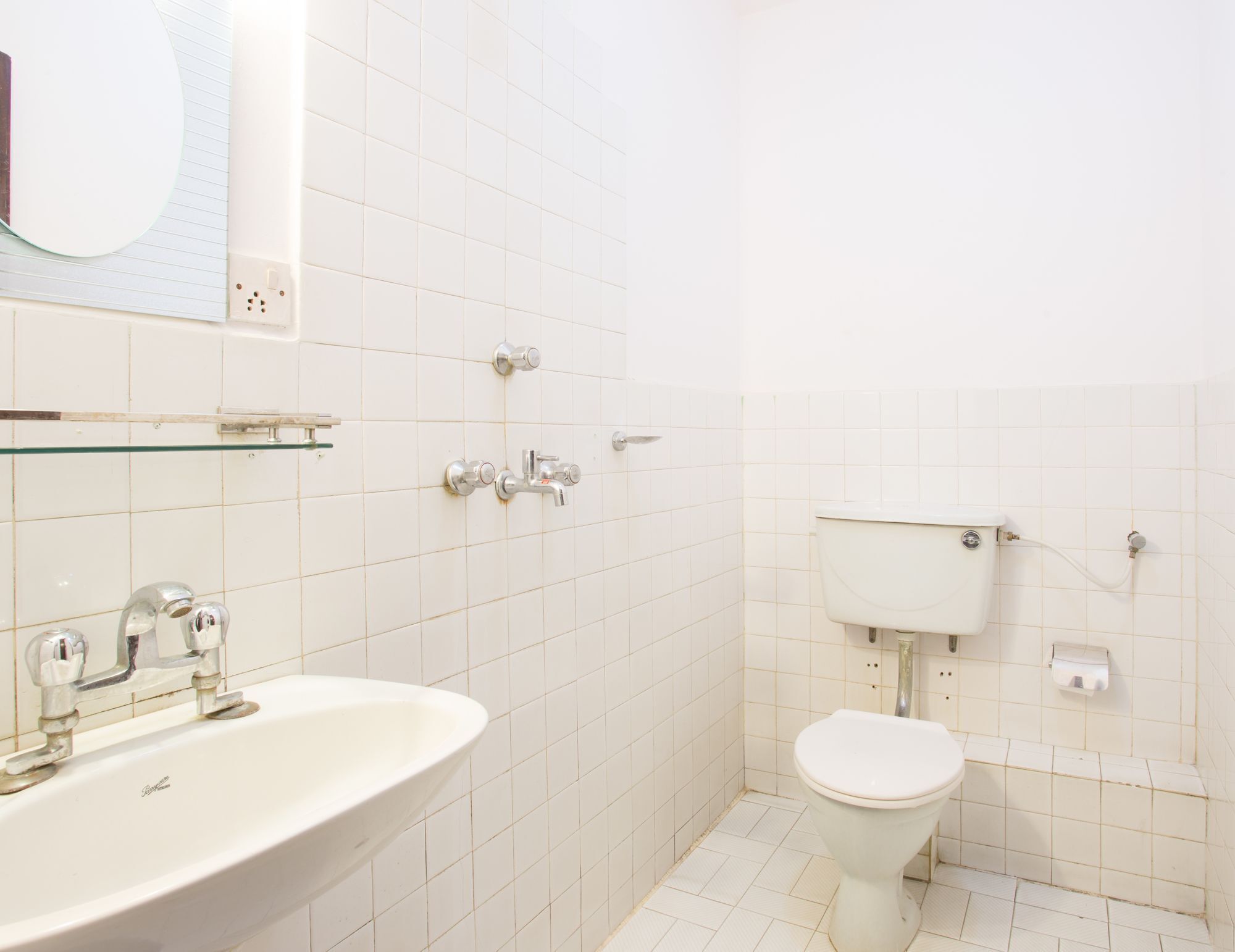 Un bany amb un lavabo blanc, un mirall i un vàter.