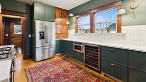 A kitchen with wooden cabinets, a stainless steel refrigerator, an oven, and a dishwasher. There is a window with a view of the outdoors. - Gorgeous private home! Central Air 4 beds, hot tub, patio, designer furnishings (Portland)
