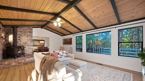 Una sala de estar acogedora con chimenea, ventanas amplias y techo de madera.