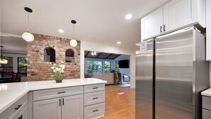 Una cocina moderna con armarios grises, un refrigerador de acero inoxidable y una pared decorativa de ladrillo.
