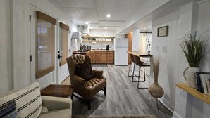 A modern kitchen with wooden cabinets, a white refrigerator, and a dining area with a wooden table and two chairs.