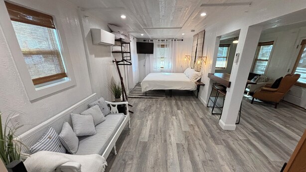 A modern bedroom with a bed, a sofa, a desk, and a chair.