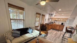 A modern living room with a sofa, coffee table, and a dining area with a chair and table.