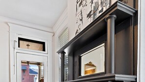 A hallway with a black fireplace, a white door, and a view of the outside. - 
Upscale 3-Story German Village Home - Near Cafés (Columbus)
