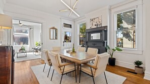 A dining area with a wooden table, six chairs, a chandelier, and a fireplace. - 
Upscale 3-Story German Village Home - Near Cafés (Columbus)