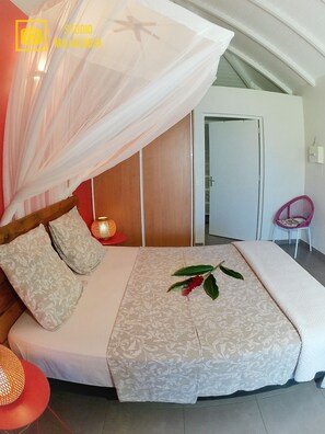 Een slaapkamer met een hemelbed, een nachtkastje met een lamp en een stoel.