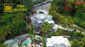 Un immeuble à plusieurs étages doté d’un espace piscine, entouré d’une végétation luxuriante et de palmiers.