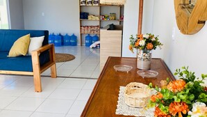 A living room with a blue sofa, wooden coffee table, and a hanging light fixture. - POUSADA LICOR DE CAJU (Cajueiro da Praia)