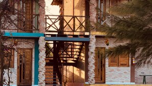A two-story building with a brick facade, a wooden staircase, and a balcony. - POUSADA LICOR DE CAJU (Cajueiro da Praia)