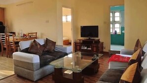 A living room with a sofa, a glass coffee table, and a television. - Bliss Apartment (Kathmandu)