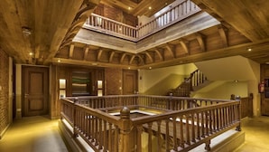 A multi-level wooden interior with a central staircase, a balcony, and a fireplace. - Nepali Ghar Hotels & Resort (Kathmandu)
