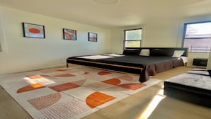 A bedroom with a bed, a bedside table, a nightstand, a window, and a floor rug.